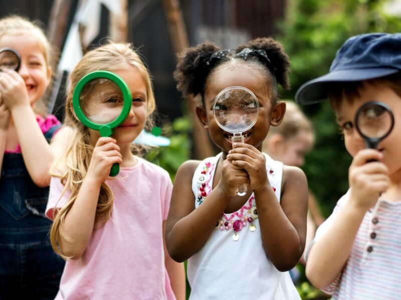 Group of kindergarten kids friends holding magnifying glass for explore